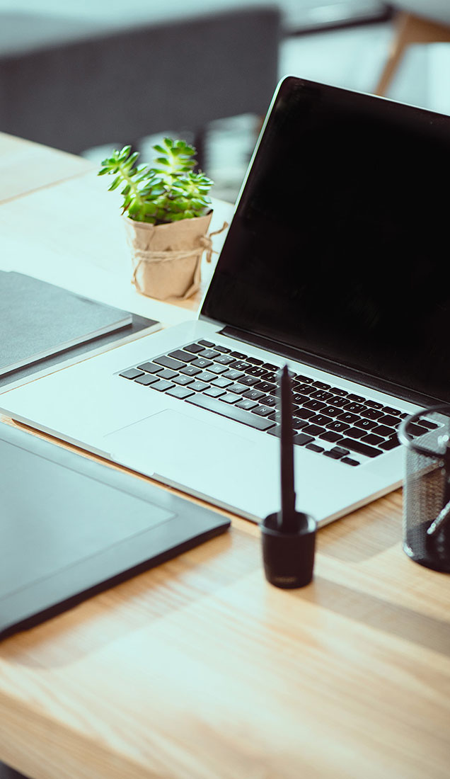 A laptop with other office supplies sat on a desk.