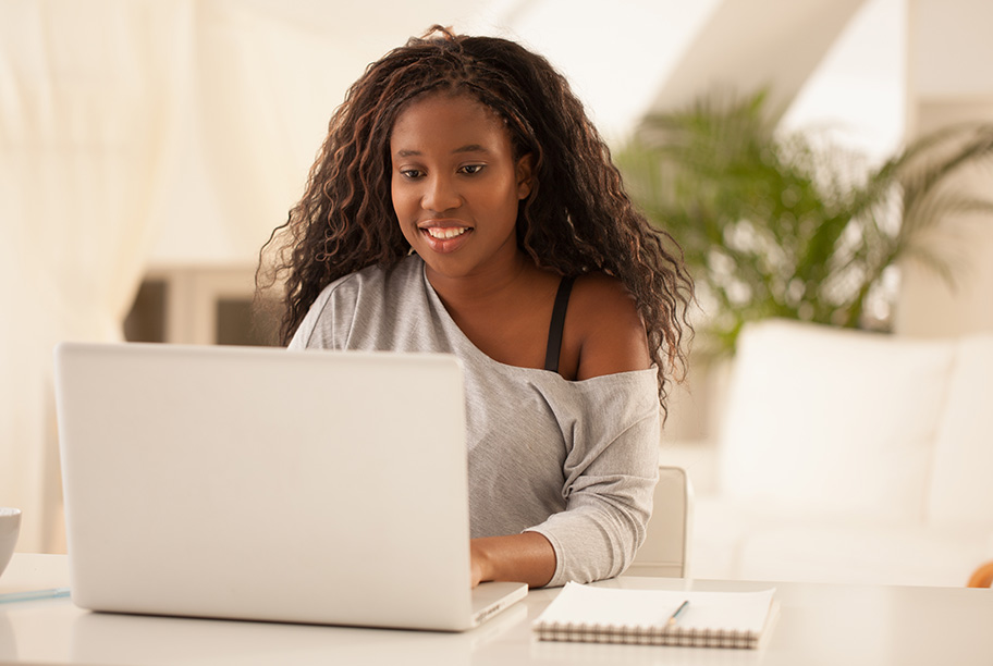 Young woman sitting at a desk with a notepad working on a computer